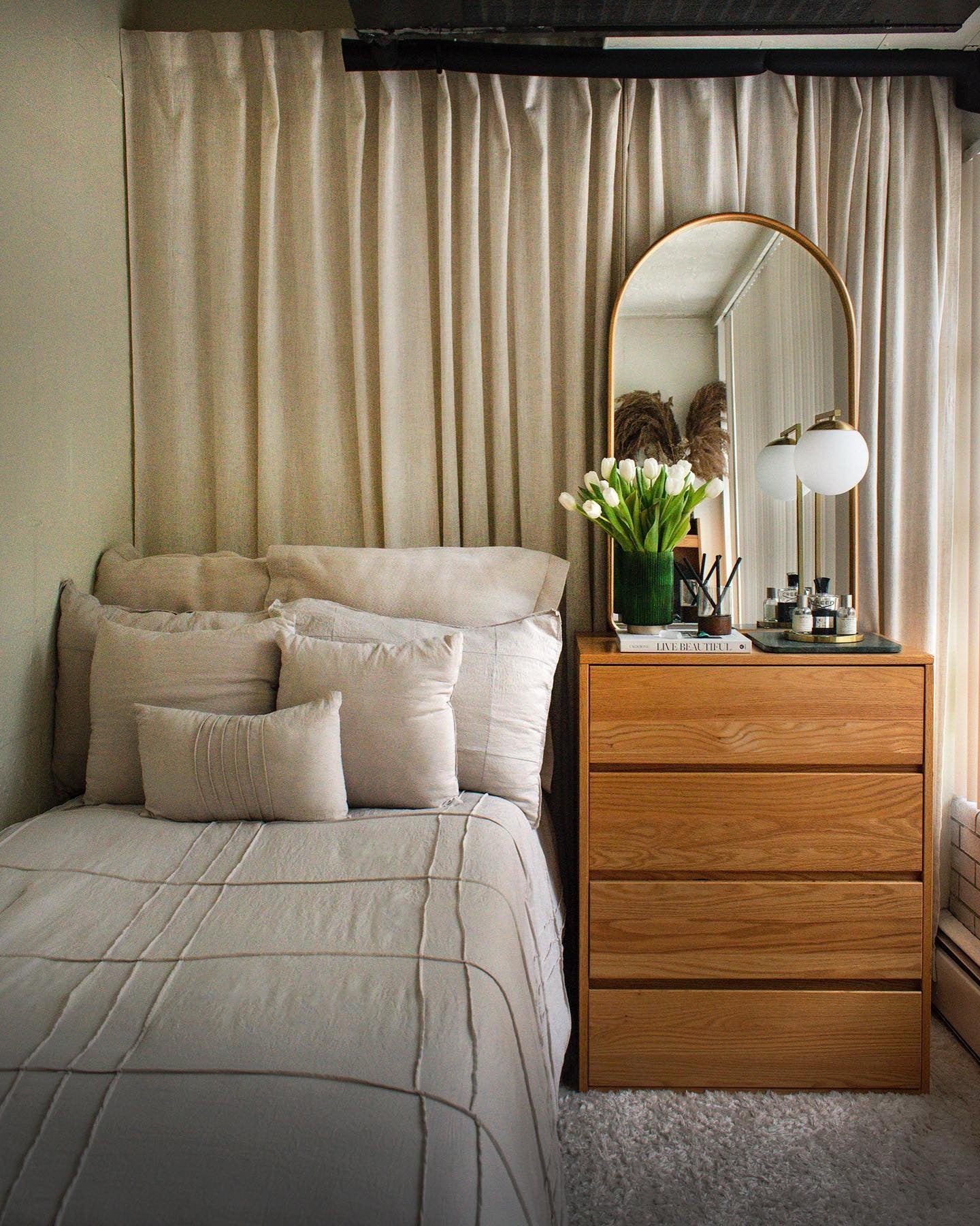 Arched gold mirror creates a soft focal point above a dresser