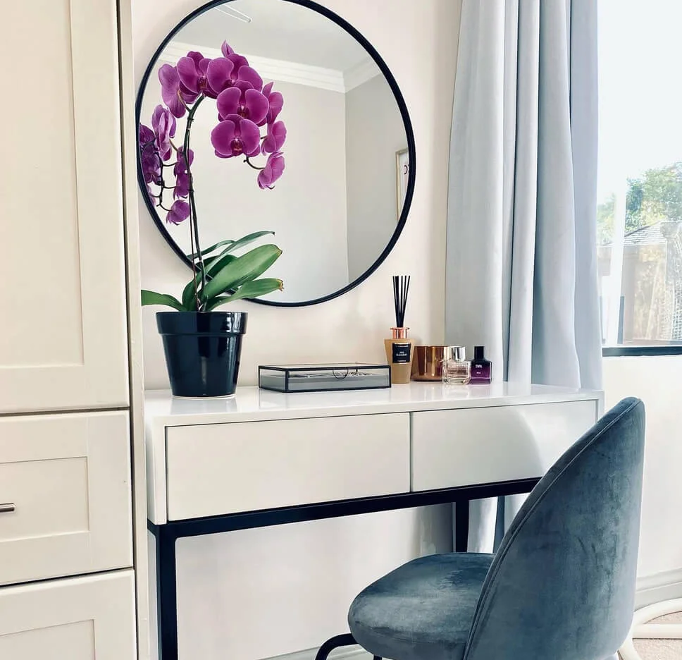 Round Mirror Reflects Orchid and Perfume Bottles