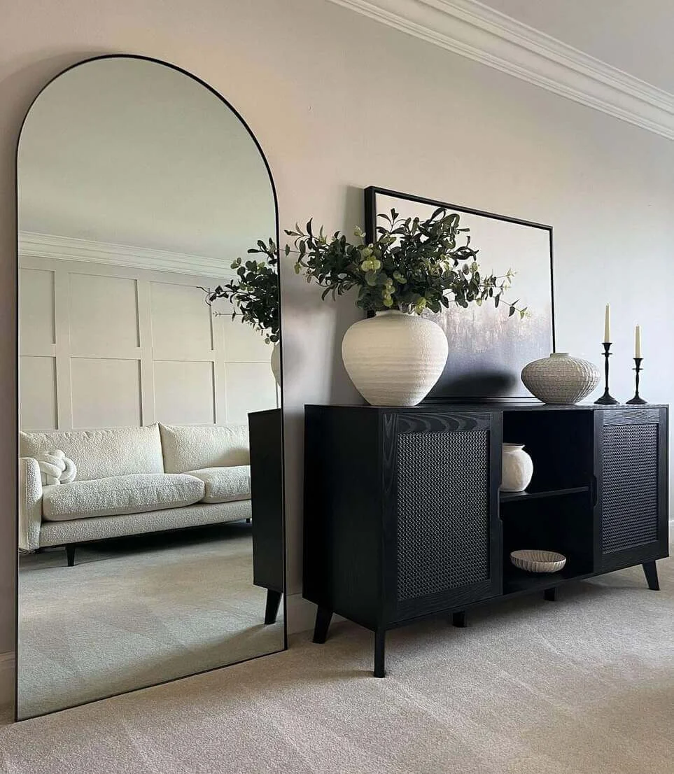 Tall Arched Mirror Reflects Paneled Wall and Sofa