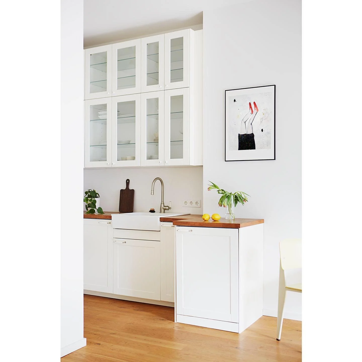 White cabinet with glass doors displays dishes and glassware